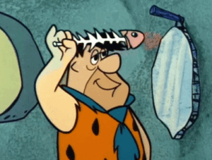 Fred Flintstone repurposing fish skeleton as a comb